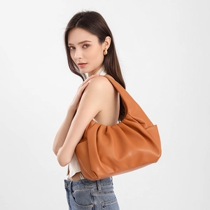 Close-up of caramel pleated cloud bag with soft leather texture on a female shoulder