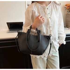 Black leather tote bag with white stitching and adjustable strap for women commuting