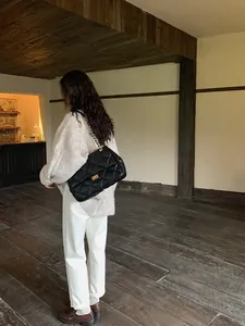 Quilted black chain bag shown on model in a cozy vintage cafe with warm lighting