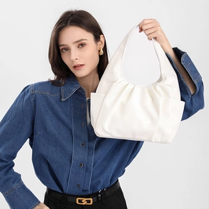Chic white pleated faux leather handbag with integrated handle worn by a model
