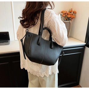 Close-up of black lychee grain tote bag with contrast white stitching and shoulder strap