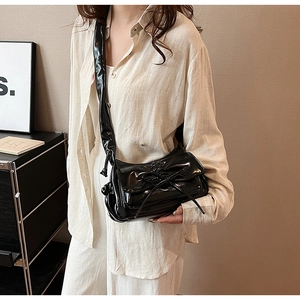 Detail of black glossy pleated cloud bag with large bow decor and wide strap