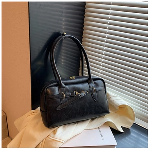Détail du sac Boston vintage noir avec boucle dorée sur un décor élégant