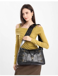 Detail of vintage black tote bag featuring multiple metal buckles and wide shoulder strap