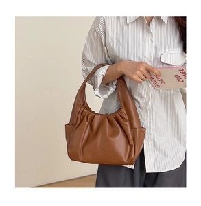 Detailed view of the brown croissant bag featuring soft pleated leather and a wide handle