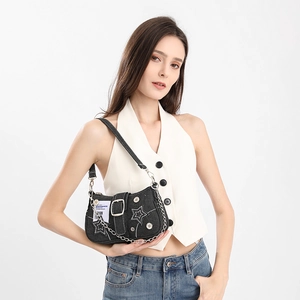Detail shot of black denim underarm bag with white star embroidery and silver metal chains