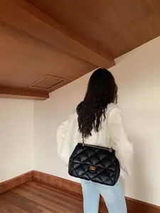 Quilted black chain bag with gold buckle shown on model in a casual outfit