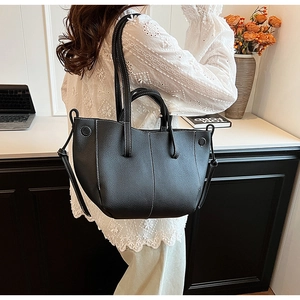 Macro view of black tote bag featuring premium lychee texture and white contrast stitching