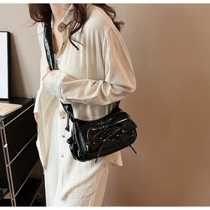 Detail of black patent leather bag with bow tie design and high-gloss finish