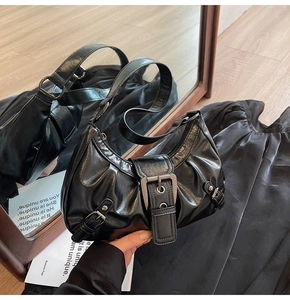 Detail view of black pleated crescent shoulder bag with a vintage large metal buckle