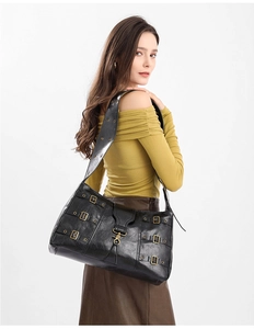 Detailed view of punk style black leather tote bag with vintage metal buckles and eyelets