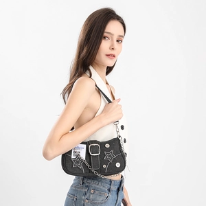 Detailed view of black denim underarm bag with star embroidery and metal chain strap