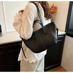 Detail of black tote bag with white contrast stitching and soft faux leather texture
