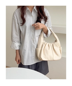 Detail of beige hobo bag showing pleated soft texture and side pocket on a model