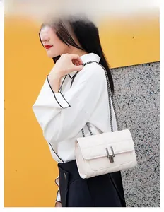 White quilted diamond crossbody bag with metallic chain strap worn by a female model