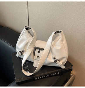 Detail view of cream white PU leather shoulder bag with chic pleated design and buckles