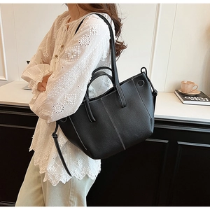 Detailed view of black lychee leather tote bag with contrasting white stitching accents