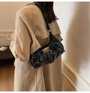Détail d'un sac baguette de style vintage noir brillant avec boucles argentées et plis chic