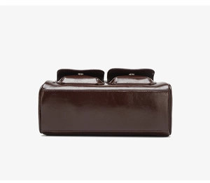 Close-up of the vintage brown waxed leather bag showing bottom stitching and dual flap pockets