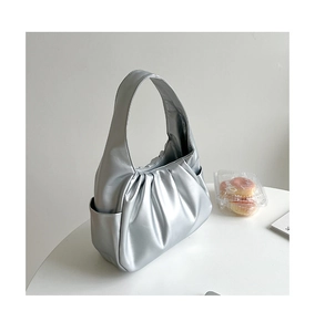 Close-up of a silver pleated hobo bag with a side pocket on a clean white table