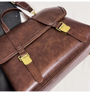 Close-up of deep brown leather texture and golden metal buckle on a retro satchel bag