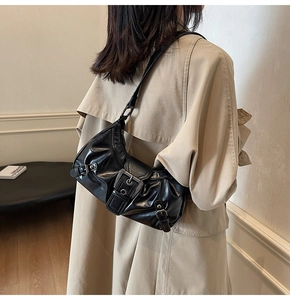 Sac porté épaule noir plissé avec boucles argentées porté sur un trench-coat beige