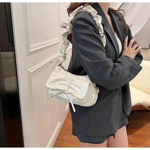 Detailed view of the shiny white patent leather shoulder bag with a bow and pleated strap
