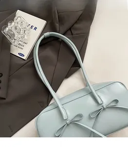 Détail du sac à main bleu clair à nœuds avec texture litchi sur un blazer marron