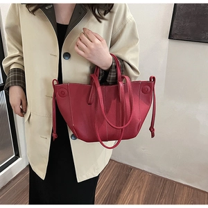 Detail of red leather tote bag showing lychee texture and white contrast stitching