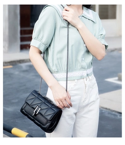 Classic black quilted crossbody bag with silver chain strap shown on a model