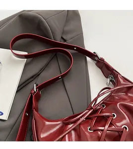 Detailed shot of dark red patent leather bag with lace-up cross ties and silver eyelets
