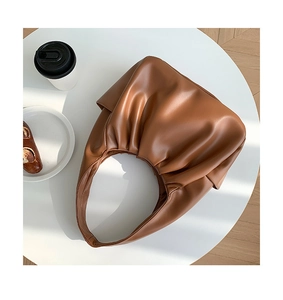 Detailed texture of brown croissant bag with soft pleated design on a white table