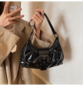 Détail du sac bandoulière vintage en cuir noir huilé avec boucle métallique et plis texturés