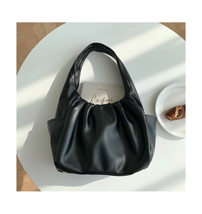 Detail of black pleated croissant bag with side pockets on a French-style table