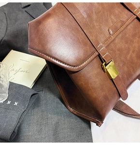 Detail of vintage brown leather backpack showing brass buckle and contrast stitching