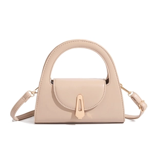 Detail of a beige semi-circle handle handbag with a gold shield-shaped metal buckle lock