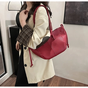 Detail view of red lychee grain leather tote bag with stylish drawstring accents