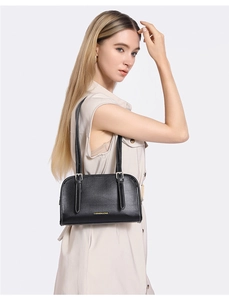 Detail of minimalist black underarm bag featuring a metallic Fashion and Bag gold logo