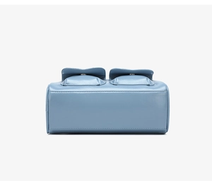Detail view of light blue oil wax leather bag featuring dual side flap pockets with stitching