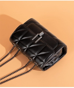 Detail shot of black quilted faux leather crossbody bag with metallic chain strap