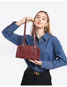 Detail of dark red leather shoulder bag featuring white contrast stitching and silver buckles
