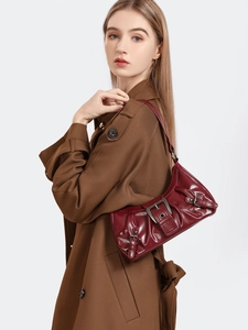 Detail of a wine red underarm bag with glossy leather and metallic buckle accents