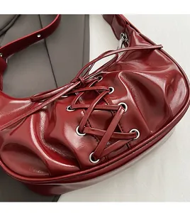 Detail of burgundy corset-style underarm bag with lace-up ribbon and metallic eyelets