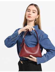 Detail view of burgundy leather crescent shoulder bag with silver buckle on a denim shirt