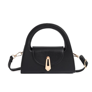 Detail of minimalist black leather trapezoid bag with gold geometric metal clasp buckle
