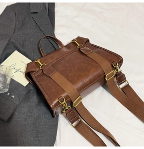 Close-up of brown vintage PU leather bag with white topstitching and gold hardware