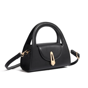 Close-up of a minimalist black semi-circle handbag featuring a gold trapezoid metal clasp