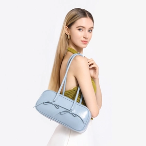 Detail of light blue bowling bag with twin bow accents and glossy leather texture