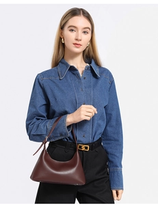 Detail of dark brown leather crescent shoulder bag styled with blue denim shirt