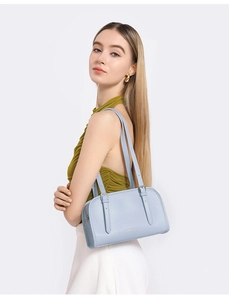 Detail of light blue leather shoulder bag with embossed logo and metal buckle strap